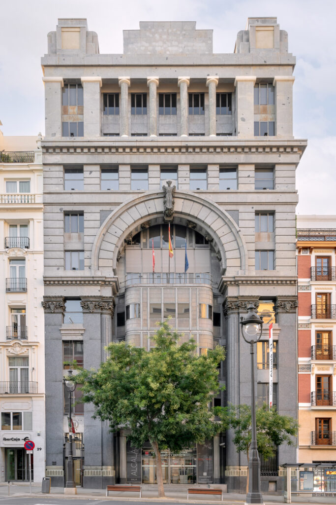 En la fachada un arco monumental aloja un mirador de acero inoxidable y cristal. Fotografía de la fachada con un arco monumental que aloja un mirador de acero inoxidable y cristal.